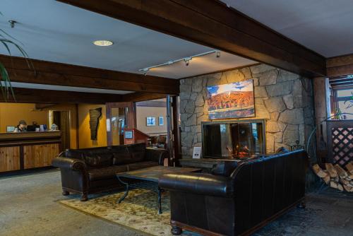 a living room with leather furniture and a stone wall at The Black Bear Lodge at Stratton Mountain Resort in Stratton Mountain