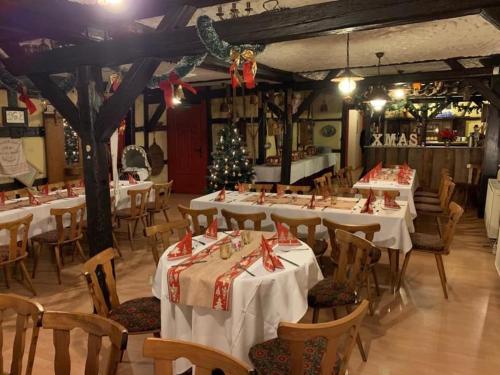 Gasthaus Zur Weintraube في باد لانغينسالزا: مطعم بطاولات بيضاء وكراسي وشجرة عيد الميلاد