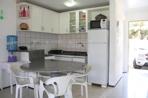 cocina con mesa y nevera blanca en APARTAMENTOS NO CARTIER PRAIA DO FUTURO FORTALEZA CONFORTAVEL COM 2 QRTOS 1 suite, en Fortaleza