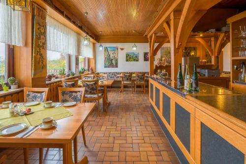 エーストリッヒ・ヴィンケルにあるPension Kühns Mühleの木製のテーブルと椅子のあるレストラン、バー