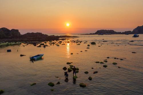 una puesta de sol sobre un cuerpo de agua con un barco en Quy Nhon Homestay BnB en Quy Nhon