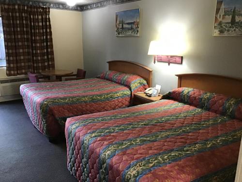 a hotel room with two beds and a table at Scottish Inns in Richmond Hill