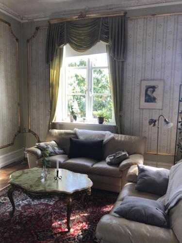 a living room with couches and a table and a window at Gamla Stan Simrishamn in Simrishamn