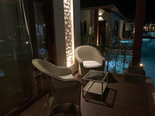 two chairs and a table on a balcony with a pool at AWARA POUSADA BOUTIQUE in São Miguel do Gostoso