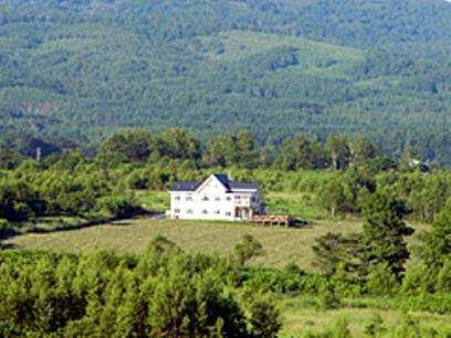 a large white house in the middle of a field at Hotel Resort Inn Niseko in Niseko