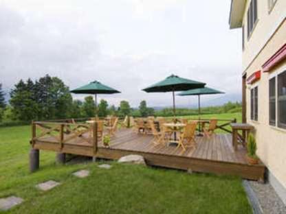 a wooden deck with tables and chairs and umbrellas at Hotel Resort Inn Niseko in Niseko