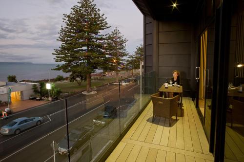 a woman sitting at a table on the balcony of a building at Vue Apartments in Napier