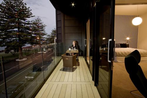a woman sitting at a table on the balcony of a building at Vue Apartments in Napier