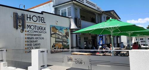 a green umbrella sitting outside of a restaurant at Hotel Motueka Backpackers, Loud Live Music Friday Saturday Nights in Motueka