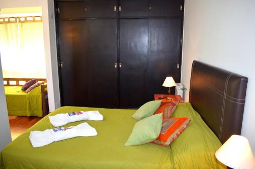 Un dormitorio con una cama verde con toallas. en Departamento Salta mi Ciudad 1 en Salta