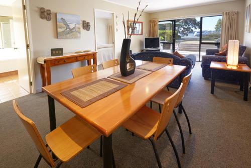 a living room with a wooden table and chairs at Pioneer Waterfront Apartments in Paihia