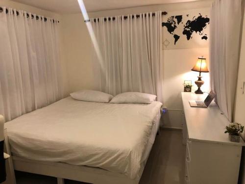 um quarto com uma cama branca e uma secretária com um candeeiro em Apartment in Nagua city center with parking 1-3 bedrooms and free WiFi em Nagua