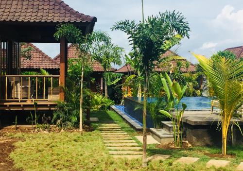 a resort with a swimming pool and palm trees at Gedong Nusa Huts in Nusa Lembongan