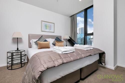 a bedroom with a large bed with a large window at QV Stays City Central Apartment with Parking in Auckland