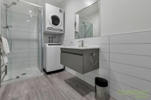 a white bathroom with a sink and a shower at QV Stays City Central Apartment with Parking in Auckland