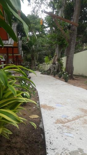 a path in a garden with trees and a building at Long Beach Garden Resort in Ko Lanta