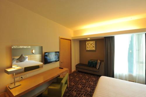 a hotel room with a bed and a desk with a mirror at The Everly Putrajaya in Putrajaya