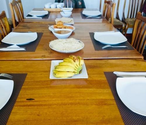 a long wooden table with a plate of bananas on it at New Royal Mount Hotel in Nuwara Eliya