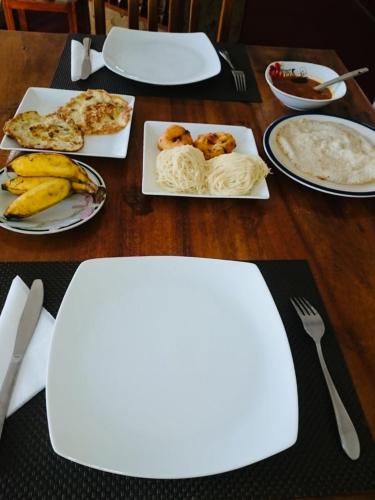 a wooden table with plates of food on it at New Royal Mount Hotel in Nuwara Eliya
