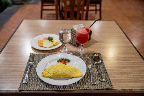 une table avec une assiette d'omelette et une boisson dans l'établissement De Munut Balinese Resort, à Ubud