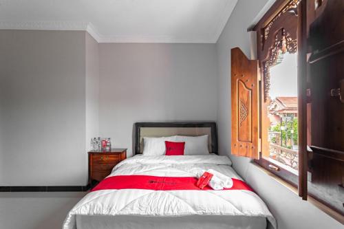 a bedroom with a bed with a red blanket and a window at RedDoorz Syariah near Exit Toll Banyumanik Semarang in Srondolwetan
