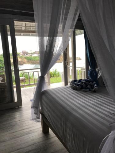 a bedroom with a canopy bed with a view of the ocean at Cliff Park Lembongan in Nusa Lembongan