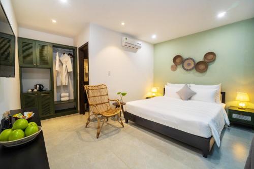 a bedroom with a bed and a chair in a room at Hoi An Gravel Pool Villa & Spa in Hoi An