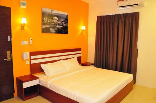 a bedroom with a bed with an orange wall at Venia Hotel Batam - CHSE Certified in Sagulung