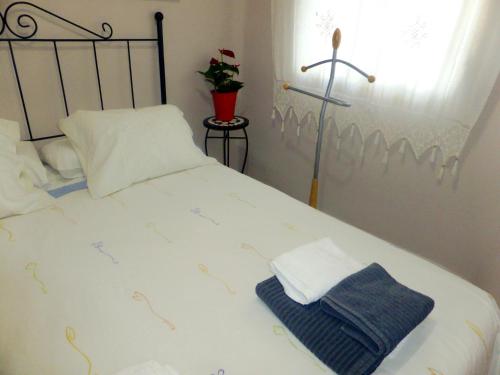 Una cama blanca con dos toallas plegables. en Esencia de Sevilla, en Sevilla