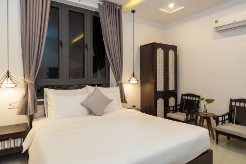 a bedroom with a large white bed and chairs at Hoi An Gravel Pool Villa & Spa in Hoi An