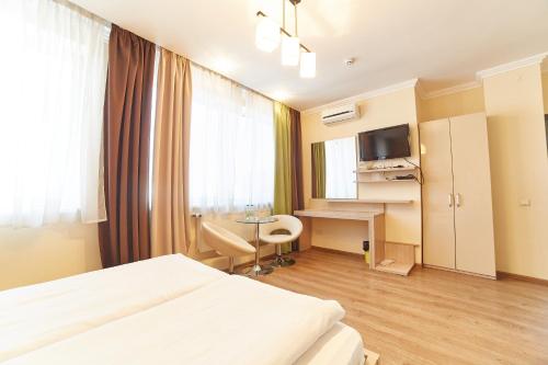 Habitación de hotel con cama, escritorio y TV. en Hotel Merkuriy, en Leópolis
