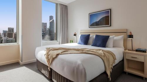 a bedroom with a large bed with a large window at Oaks Melbourne on Market Hotel in Melbourne