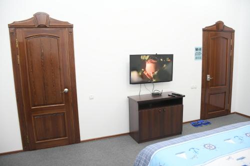 1 dormitorio con 1 cama y TV en la pared en Nurziyo Guest House, en Tashkent