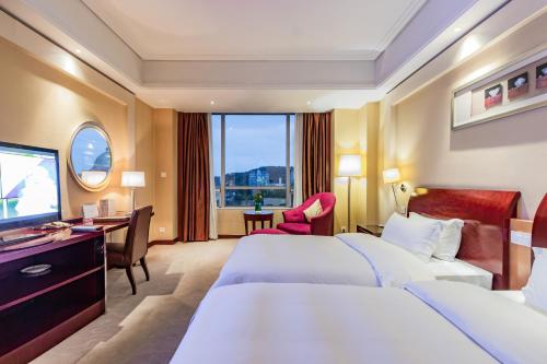 a hotel room with two beds and a desk and a television at Plaza Hotel Yuyao in Yuyao