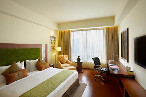 a hotel room with a large bed and a desk at Radisson Blu Hotel Rudrapur in Rudrapur