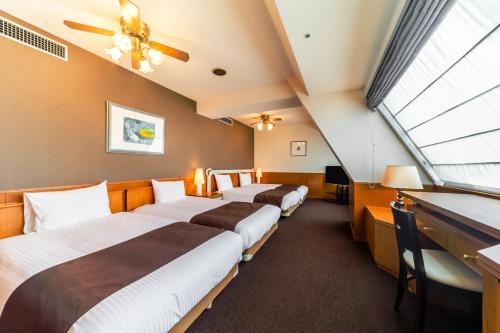 a row of beds in a room with a window at Nest Hotel Sapporo Odori in Sapporo