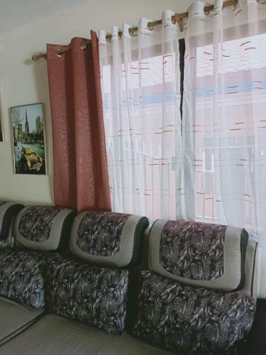a couch sitting in front of a window with curtains at Villa Cresenciana in Batuan