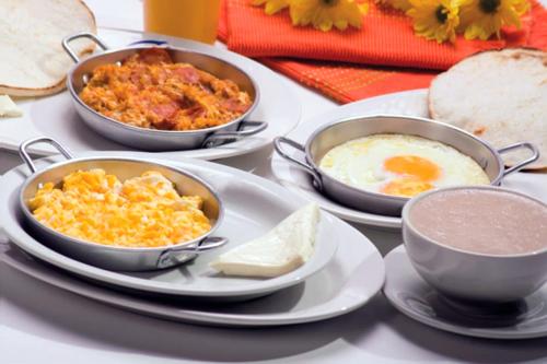薩蘭托的住宿－Refugio Nidos del Condor Cocora，一张桌子,上面放着三盘食物、鸡蛋和面包