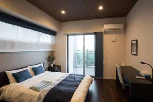 1 dormitorio con cama, escritorio y ventana en Ocean Resort 101 B32, en Shioya