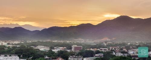 a city with mountains in the background at sunset at JOMSTAY Majestic Ipoh Suites in Ipoh