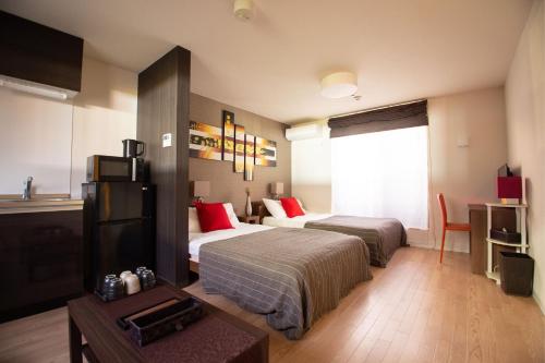 ein Hotelzimmer mit 2 Betten und einem TV in der Unterkunft Apartment Hotel STAY THE OSAKA in Izumi-Sano