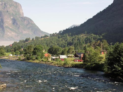 a river with a village and mountains in the background at Lunde Camping in Aurland