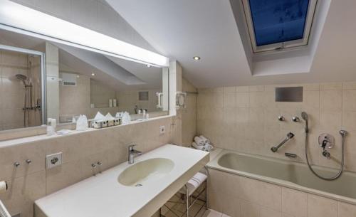 a bathroom with a sink and a tub and a mirror at Landgasthaus & Hotel Kurfer Hof in Bad Endorf