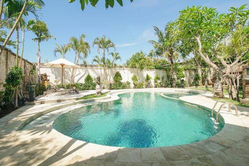 a swimming pool in a yard with trees at Baliana Villa Legian in Legian