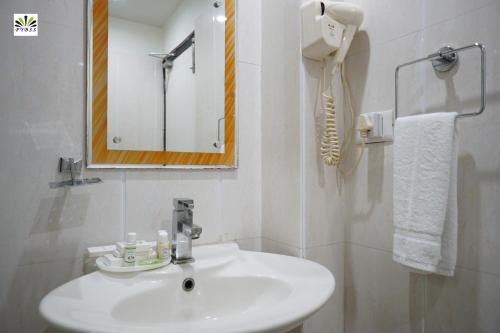 a white bathroom with a sink and a mirror at Hotel Pybss in Itānagar