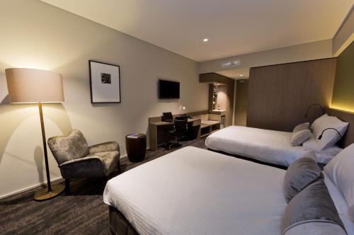 a hotel room with two beds and a desk at Glen Hotel and Suites in Brisbane