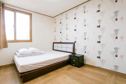 a bedroom with a bed with white walls and a window at Jeju Special Pension in Jeju