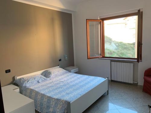um quarto com uma cama e uma janela em la casa blu em Roccella Ionica