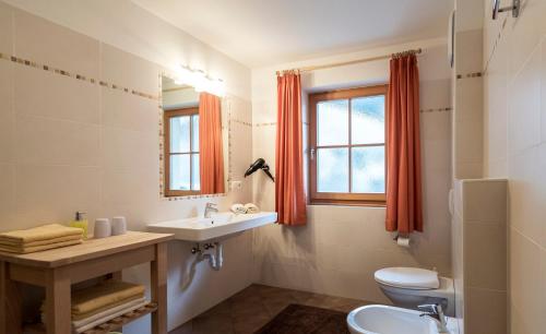 ein Bad mit einem Waschbecken, einem WC und einem Fenster in der Unterkunft Apartments Obereggerhof in Vals