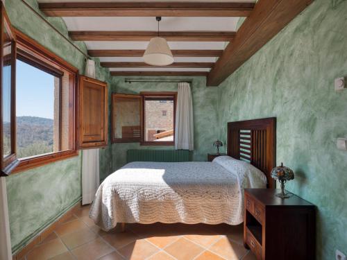 a bedroom with a bed with green walls and a window at Casa del Moliner in Boada